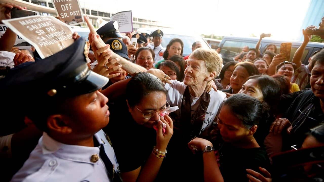Australian nun Sister Patricia Fox is surrounded by supporters and media as she leaves the Philippines.