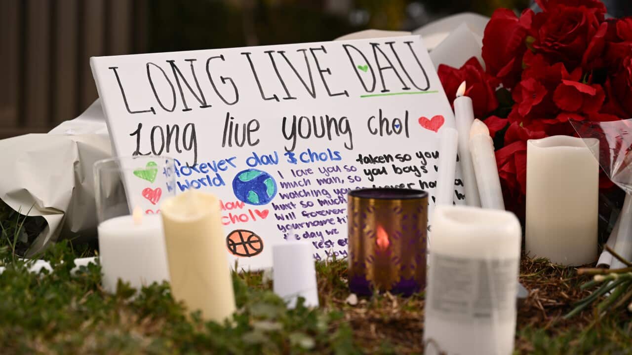 Candles and flowers laid on a ground near a sign that says “Long live Dau, long live young Chol“.