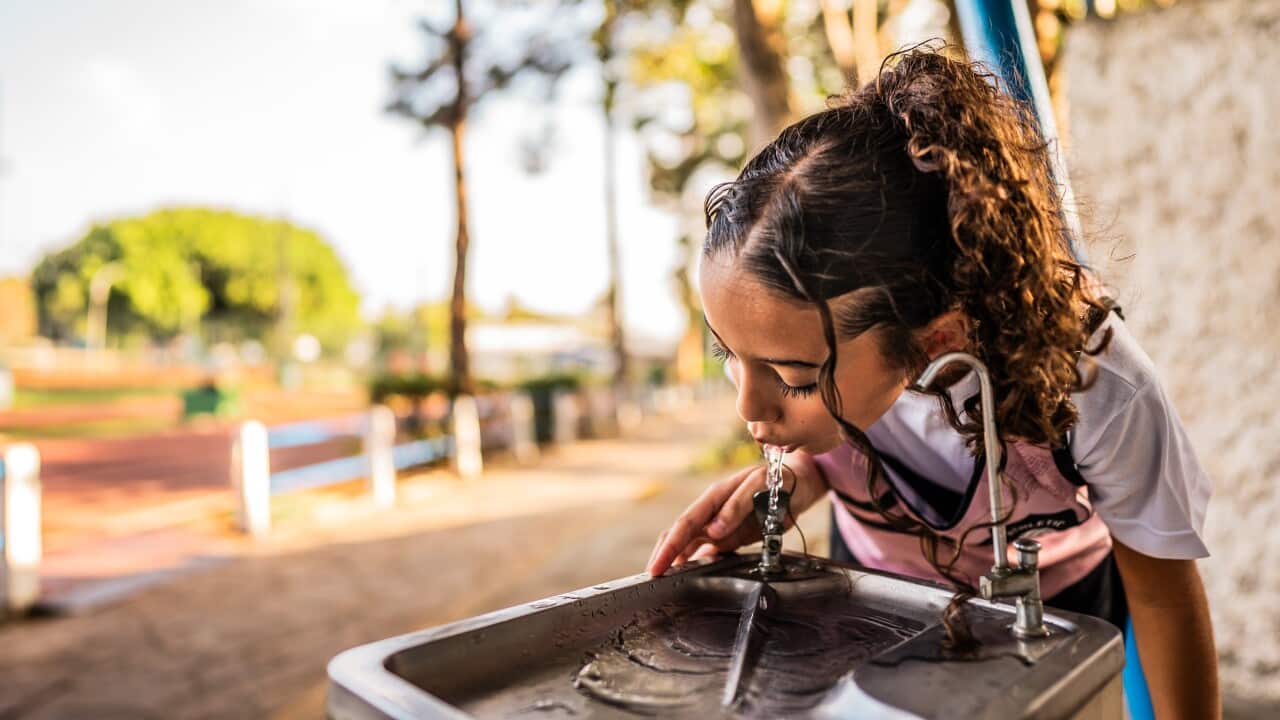 A girl drinking water on a running track.