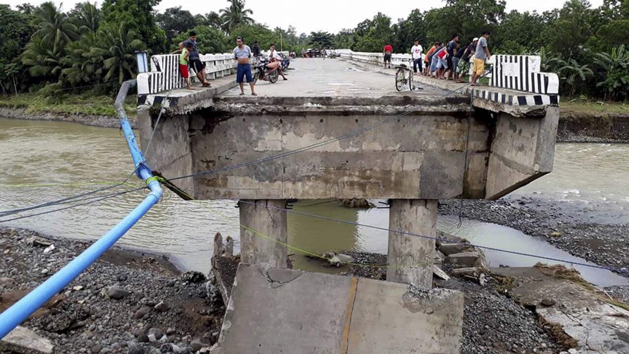 People gather on a bridge damaged by flooding from tropical storm Tembin.