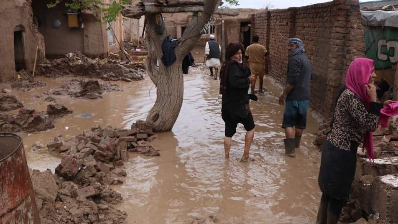 Afghan people survey their damaged houses after floods.