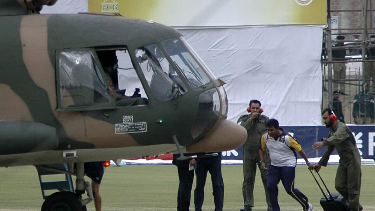 A cricketer is escorted into a helicopter at a cricket station