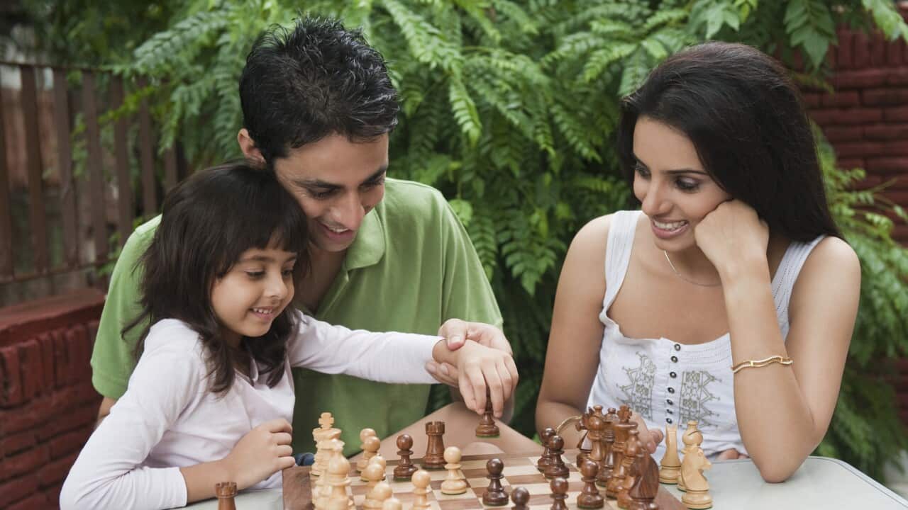 Girl playing chess with her parents
