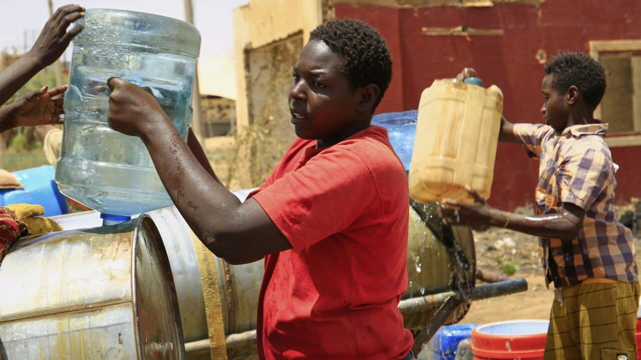 People fill a container by water due to water outages in Khartoum, Sudan.