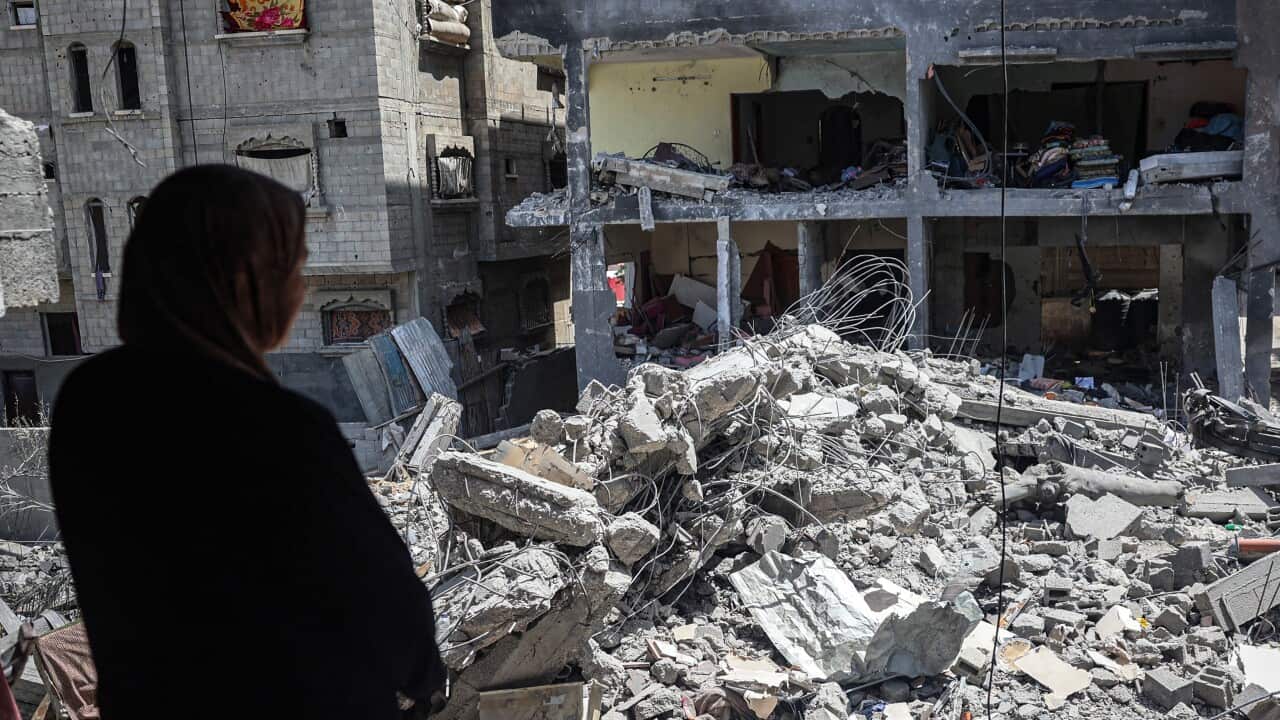 A woman stands looking over a pile of rubble
