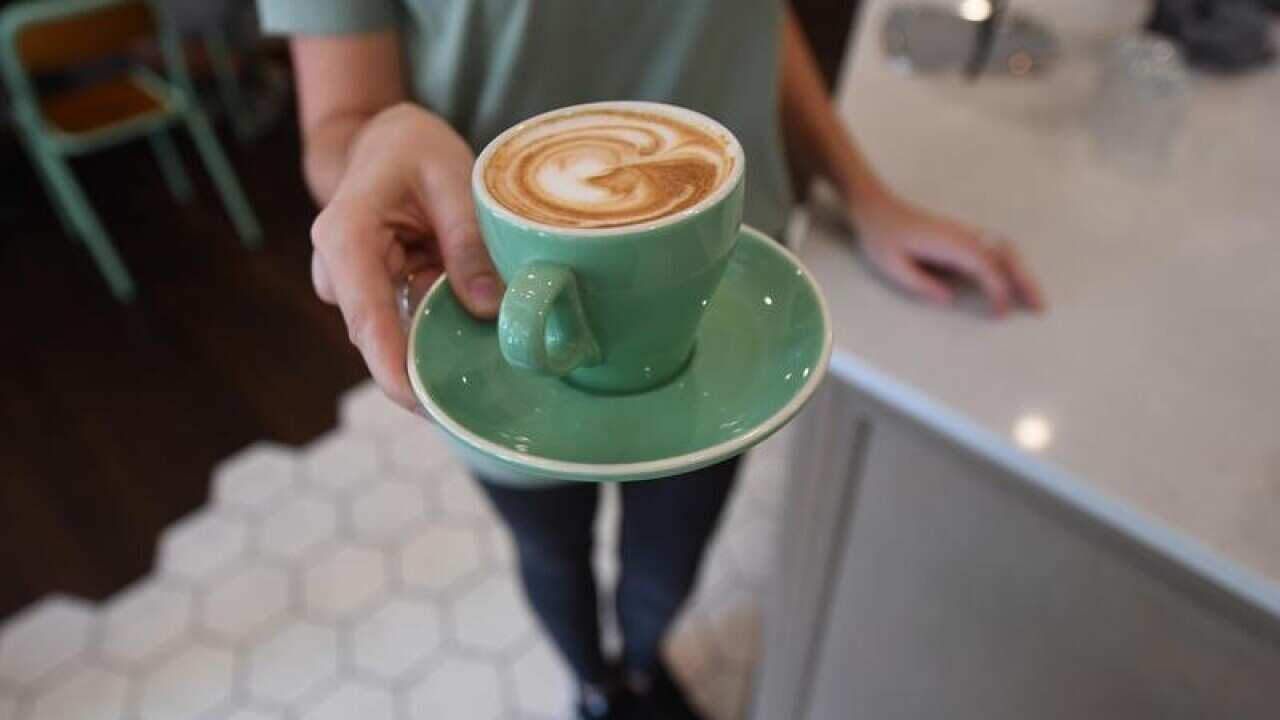 A waitress is seen holding a coffee at a cafe