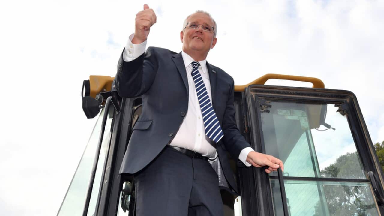 Prime Minister Scott Morrison climbs out of the cabin of a loader during a visit to the landscaping business