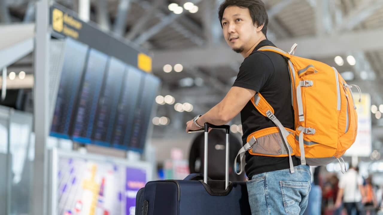 Portrait of Asian traveler with luggage with passport standing o