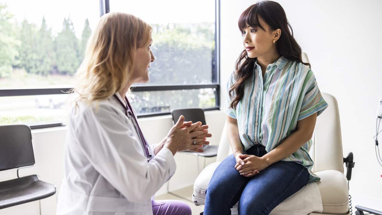 Female doctor talking with young woman in exam room