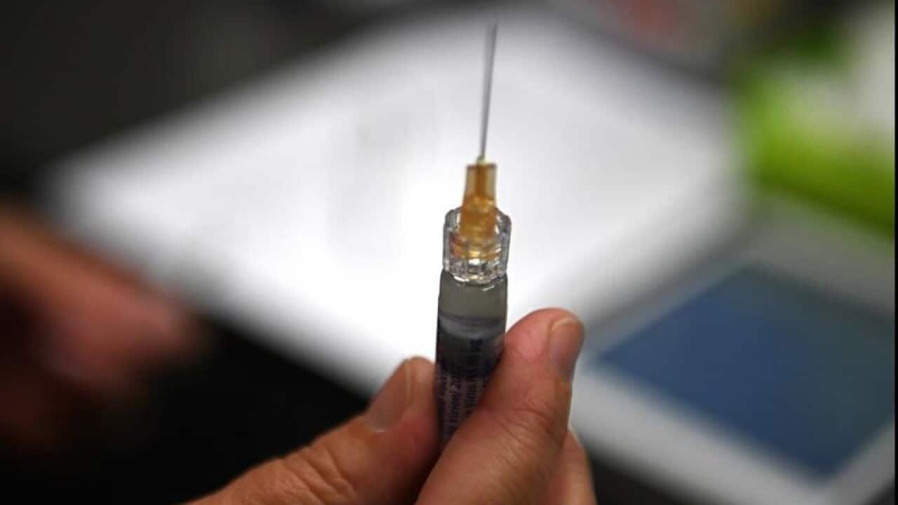 Close up of hand holding a syringe