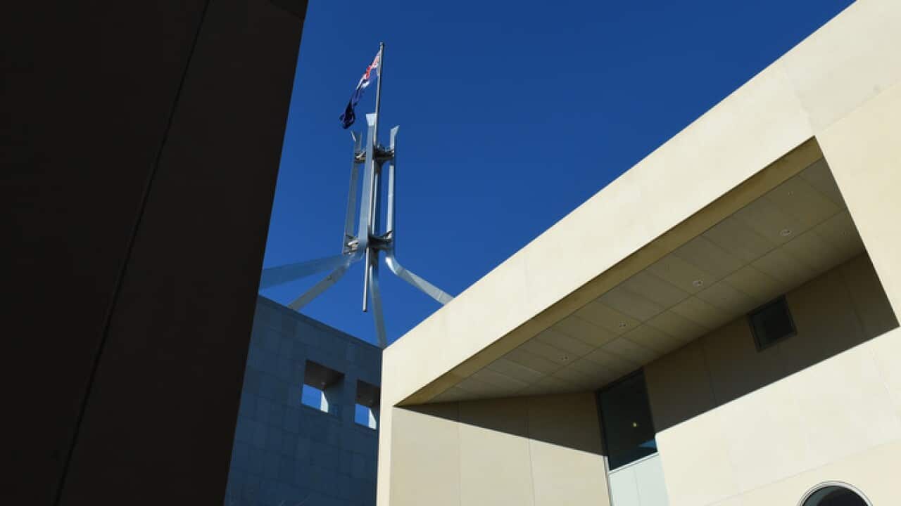 The Australian flag is seen above Parliament House in Canberra