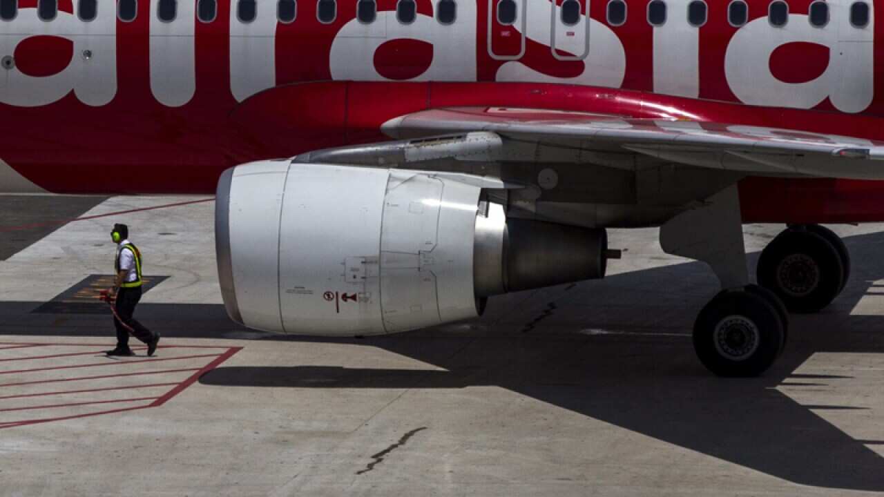 Air Asia crew member walks near their aircraft