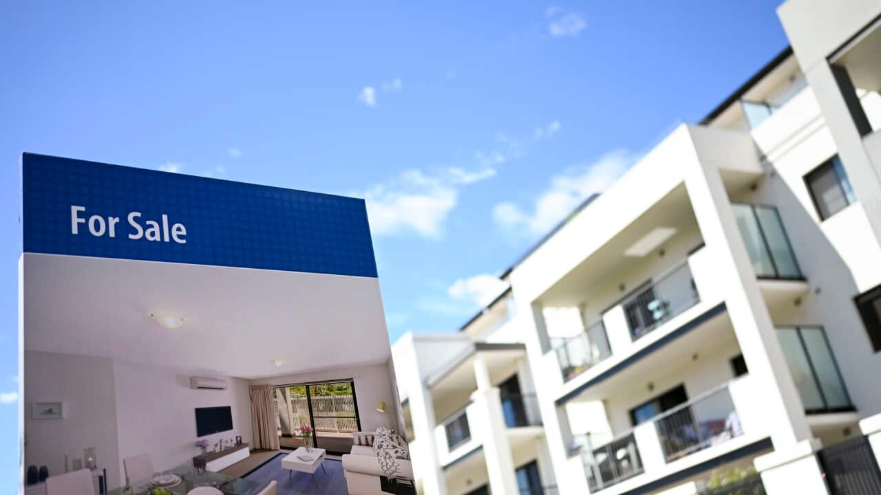A row of apartments with a 'for sale' sign in front.