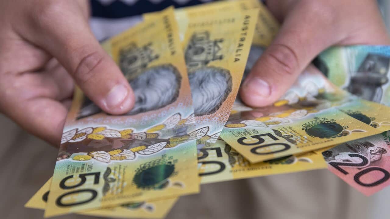 A pair of hands holding an assortment of Australian cash