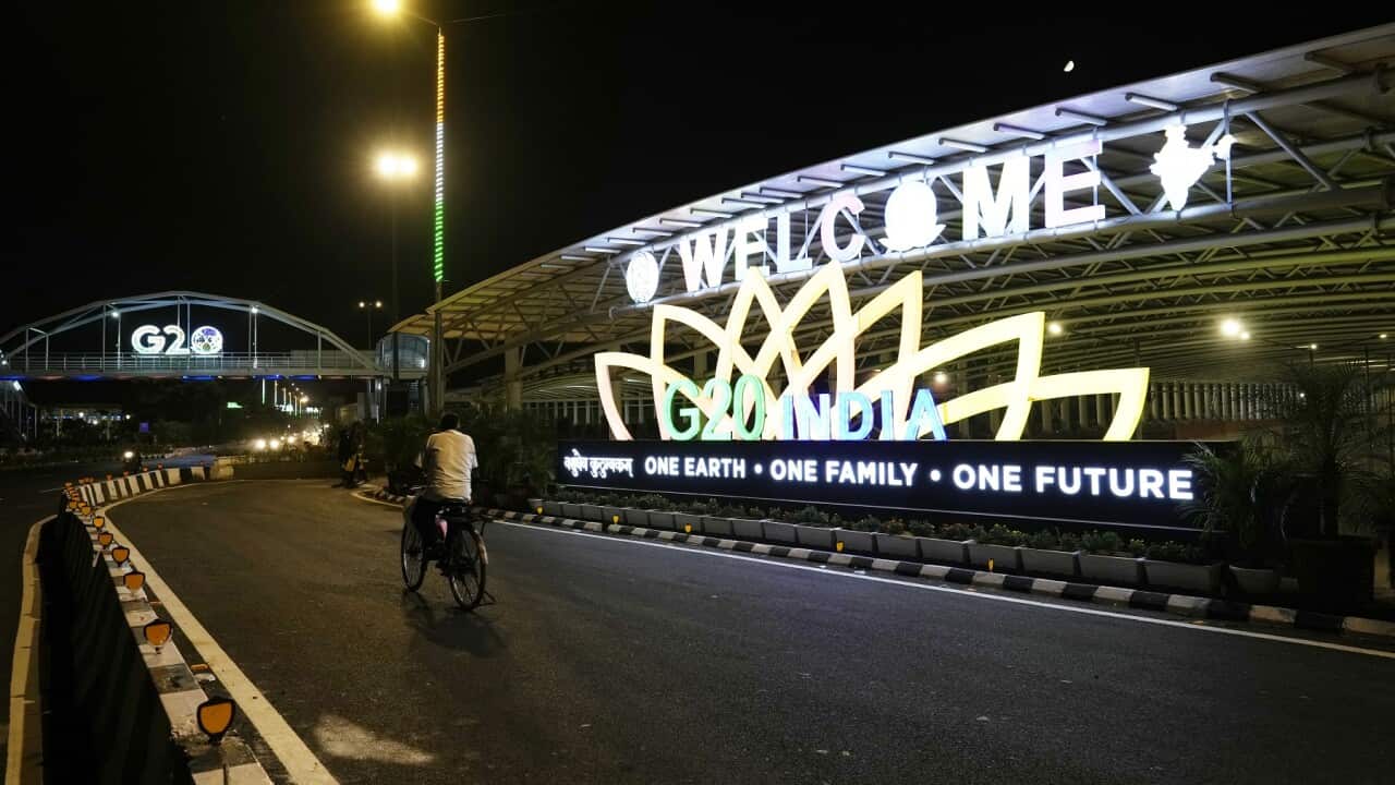 A cyclist pedals past a G20 logo near the main venue of the summit, in New Delhi (AAP)