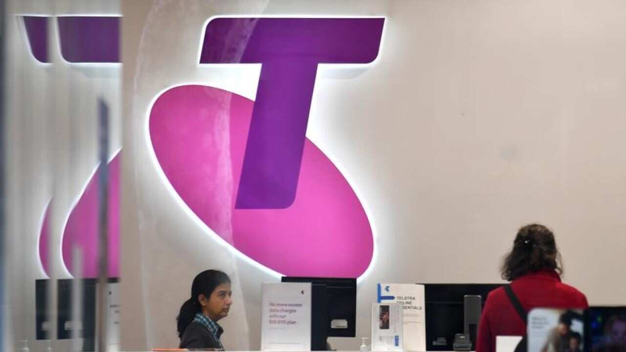 Customers and assistants are seen in a Telstra store.