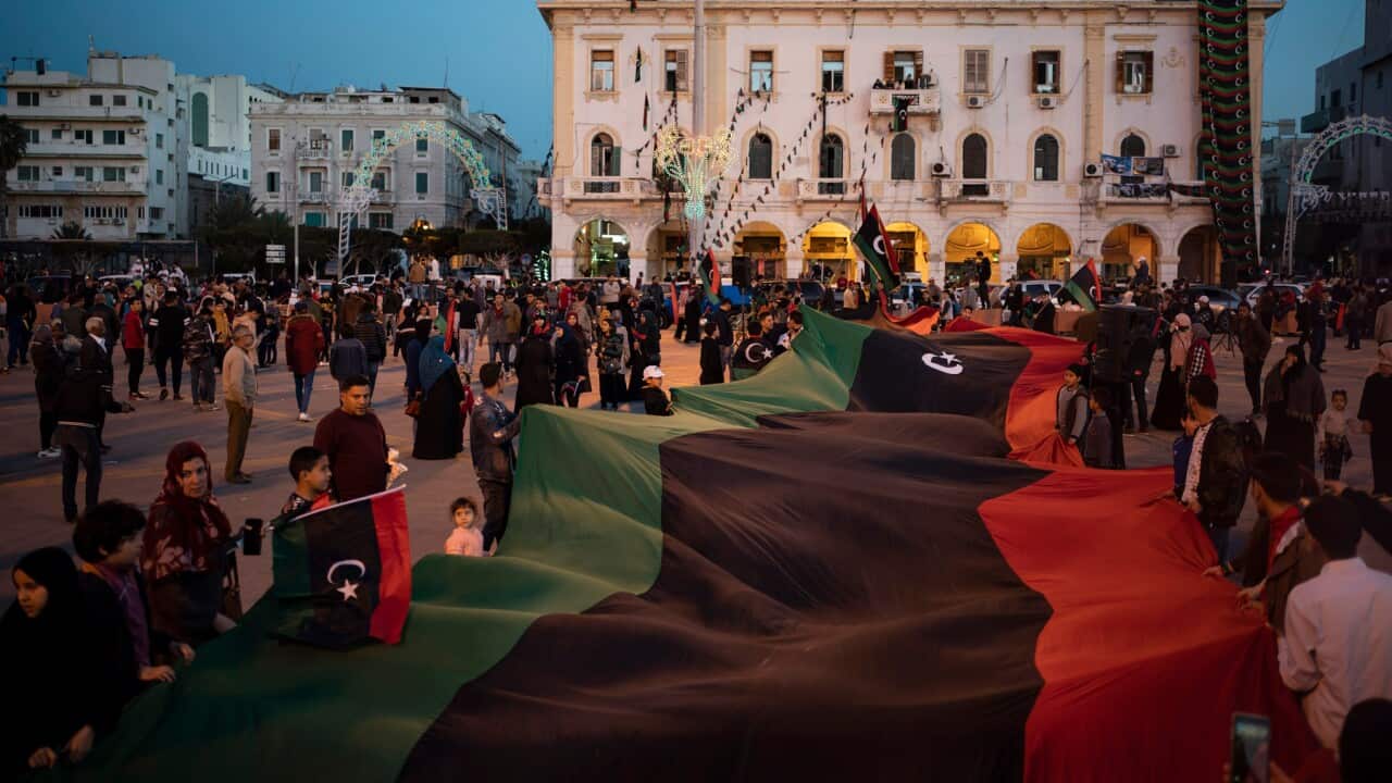 People carry a giant Libyan flag at the Martyr square commemorating the fall of Moammar Gadhafi