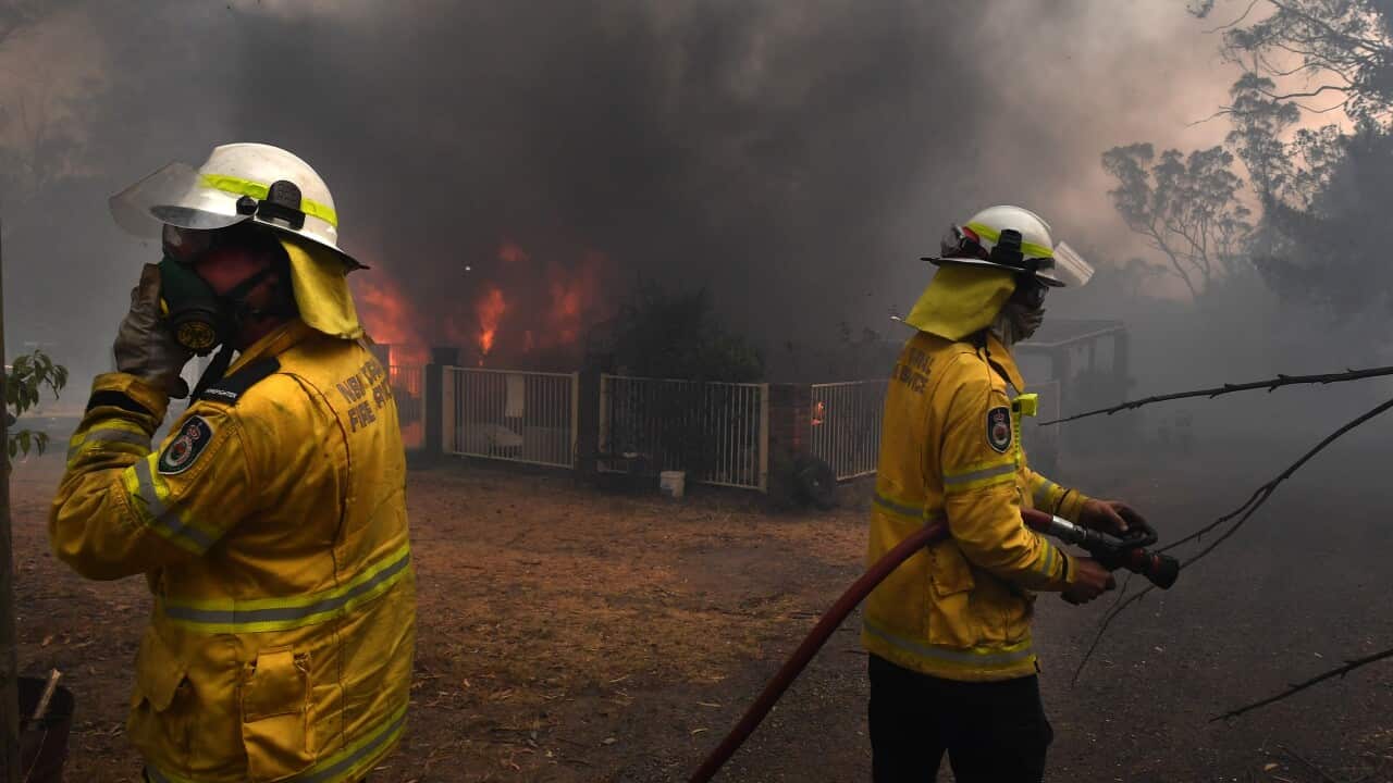 Rural Fire Service crews douse a home lost to the Green Wattle Creek Fire in the south-west of Sydney.