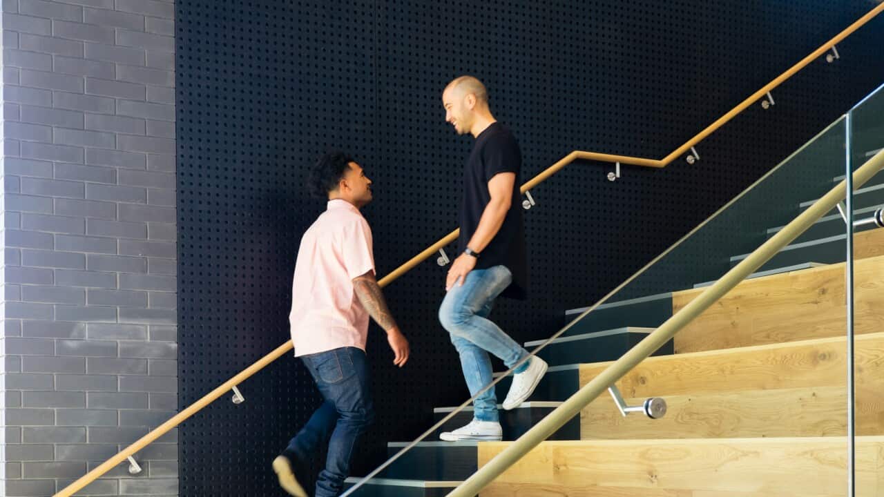 Two men smiling as they pass each other