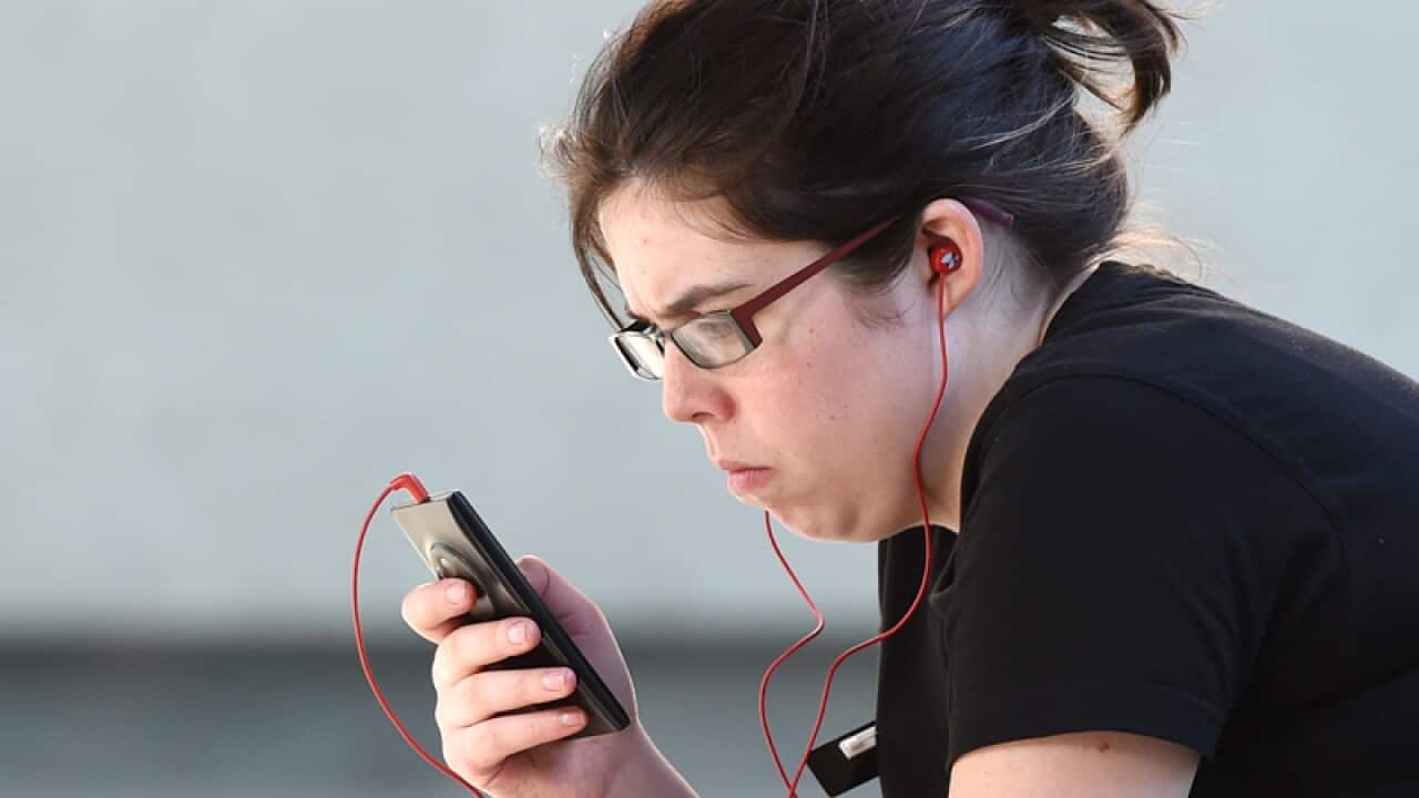 A young woman looks at her mobile phone