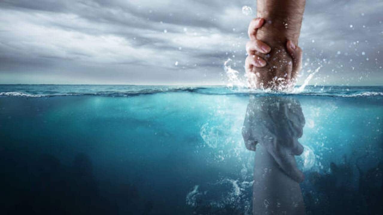 A hand reaches down into the water and saves someone drowning.