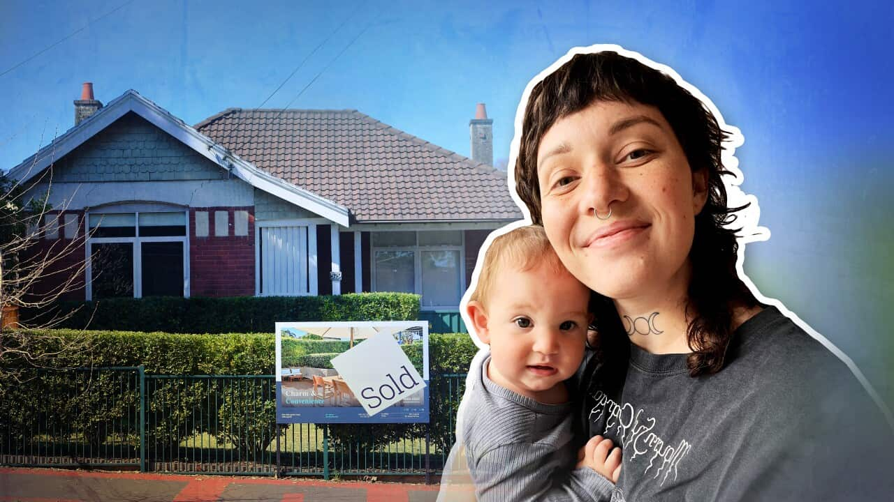 A young woman holds a baby in front of a house