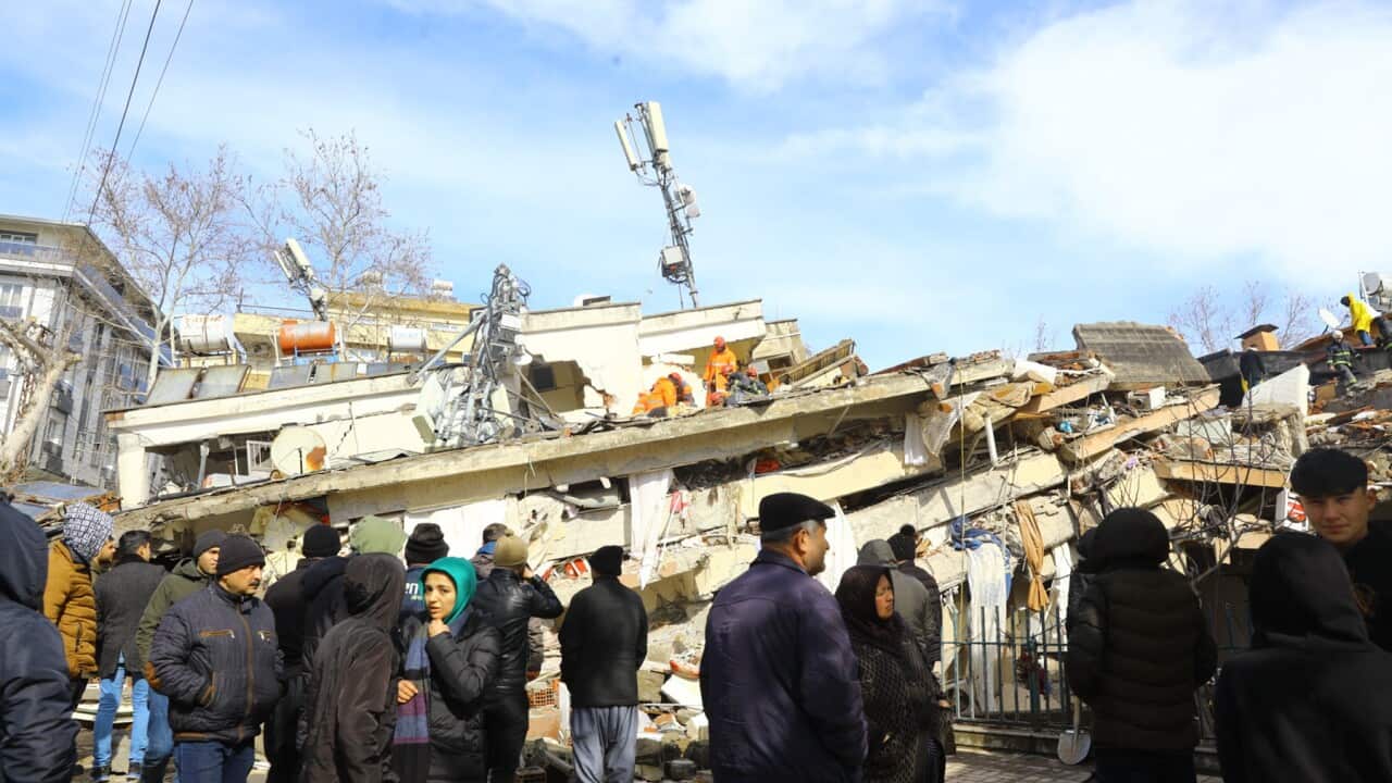Residents look on at collapsed buildings in piles in south Turkey