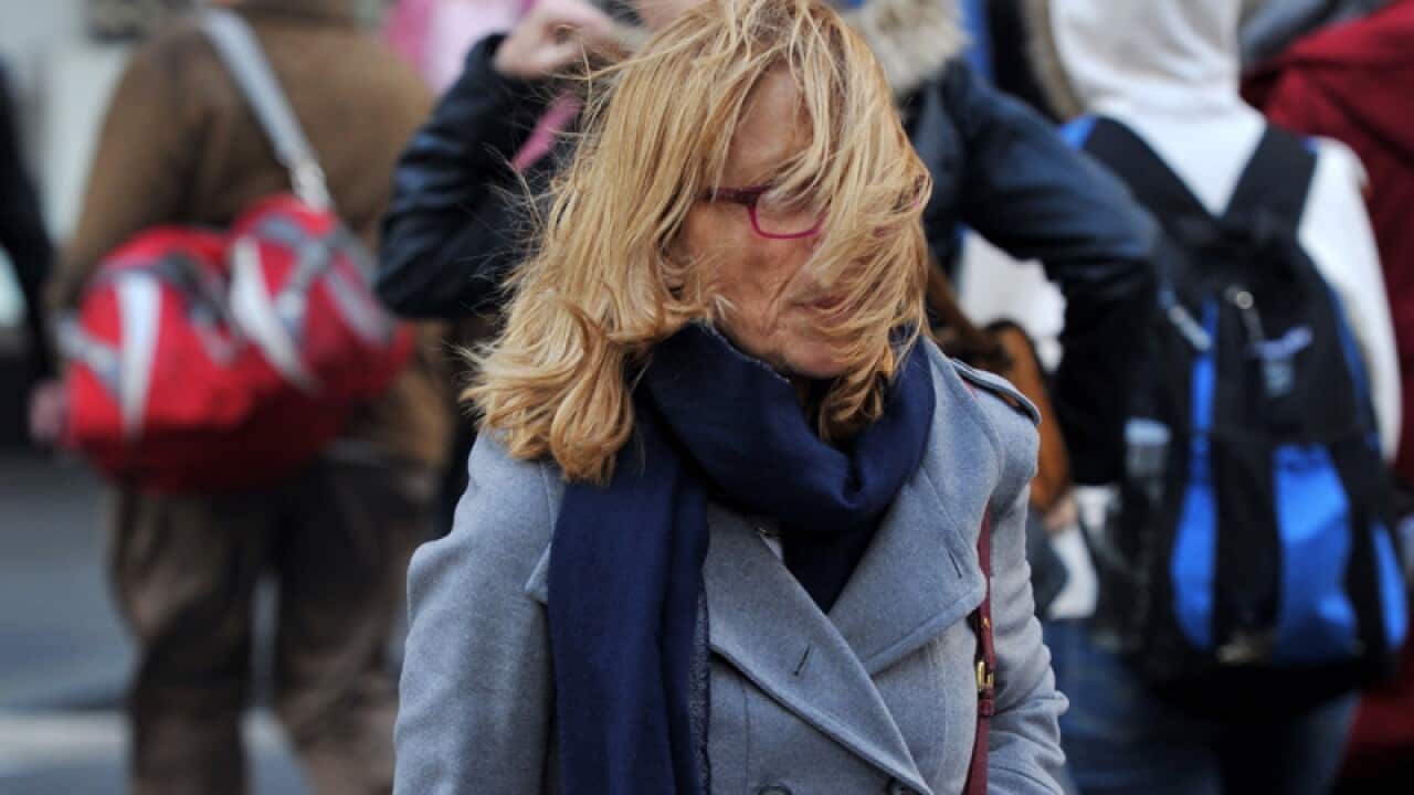 A pedestrian is buffeted by wind