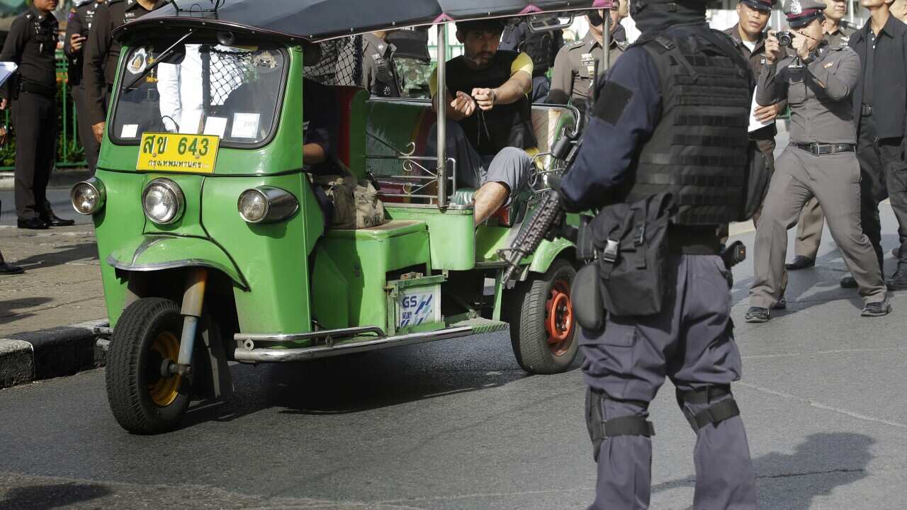 Police officers escort a key suspect in last month's Bangkok bombing (AP Photo/Sakchai Lalit)