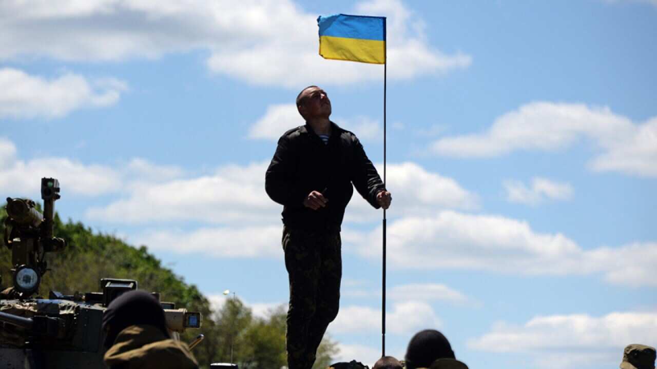 Ukrainian solders set up a Ukrainian flag on an armoured vehicle