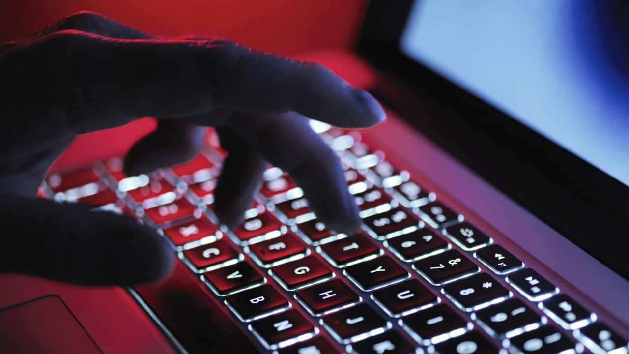 A dark mystery hand typing on a laptop computer at night.