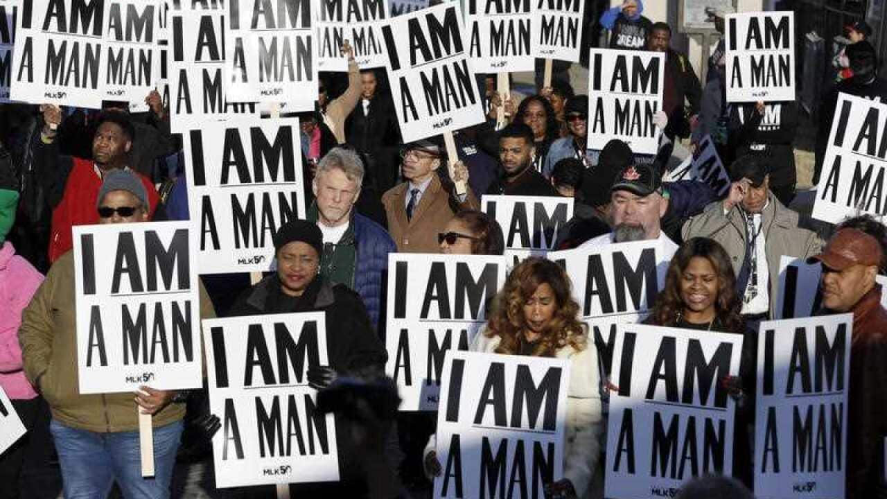 People hold signs, resembling the signs carried by striking sanitation workers in 1968, at the 50th anniversary of the assassination of Martin Luther King