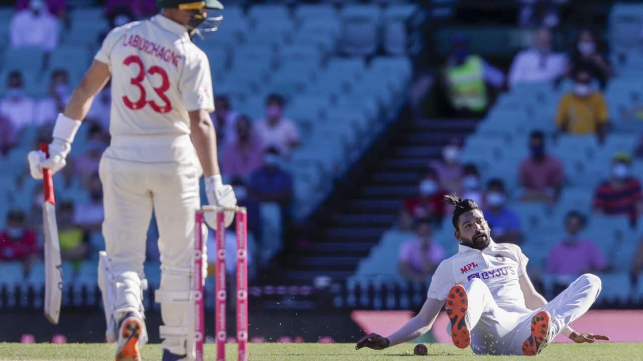 India's Mohammed Siraj falls as he fields the ball hit by Australia's Marnus Labuschagne, left, during play on day three of the third cricket test.