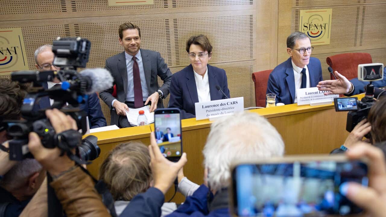 A woman sitting at a table during a press conference