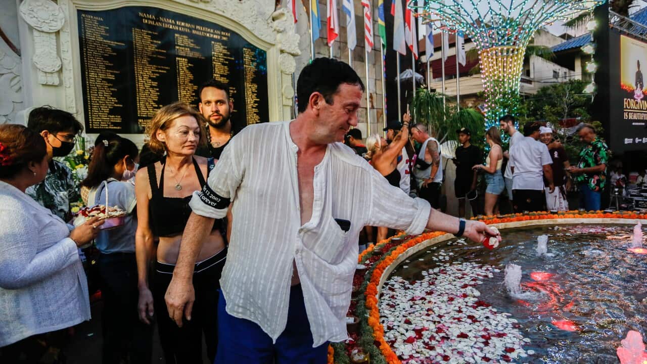 Man putting flowers on remembrance piece.