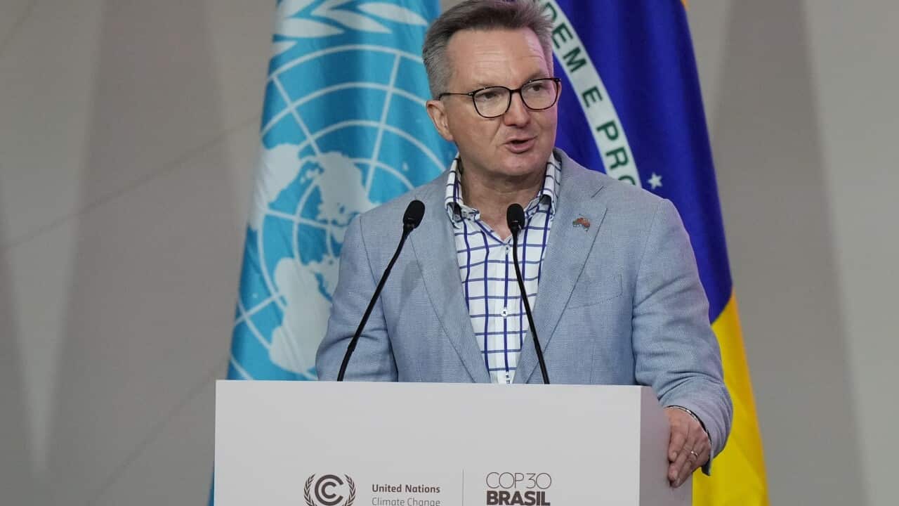 Man in a grey blazer speaking at podium.