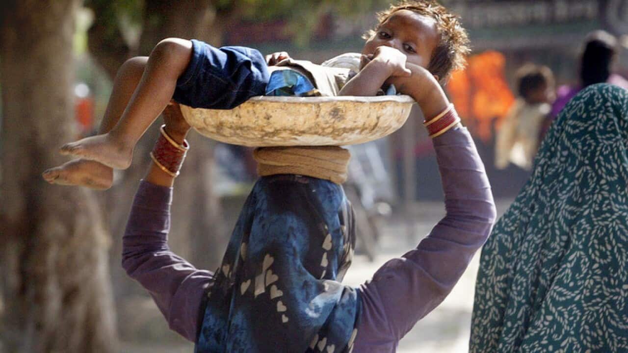 A woman carrying her child to work in India.