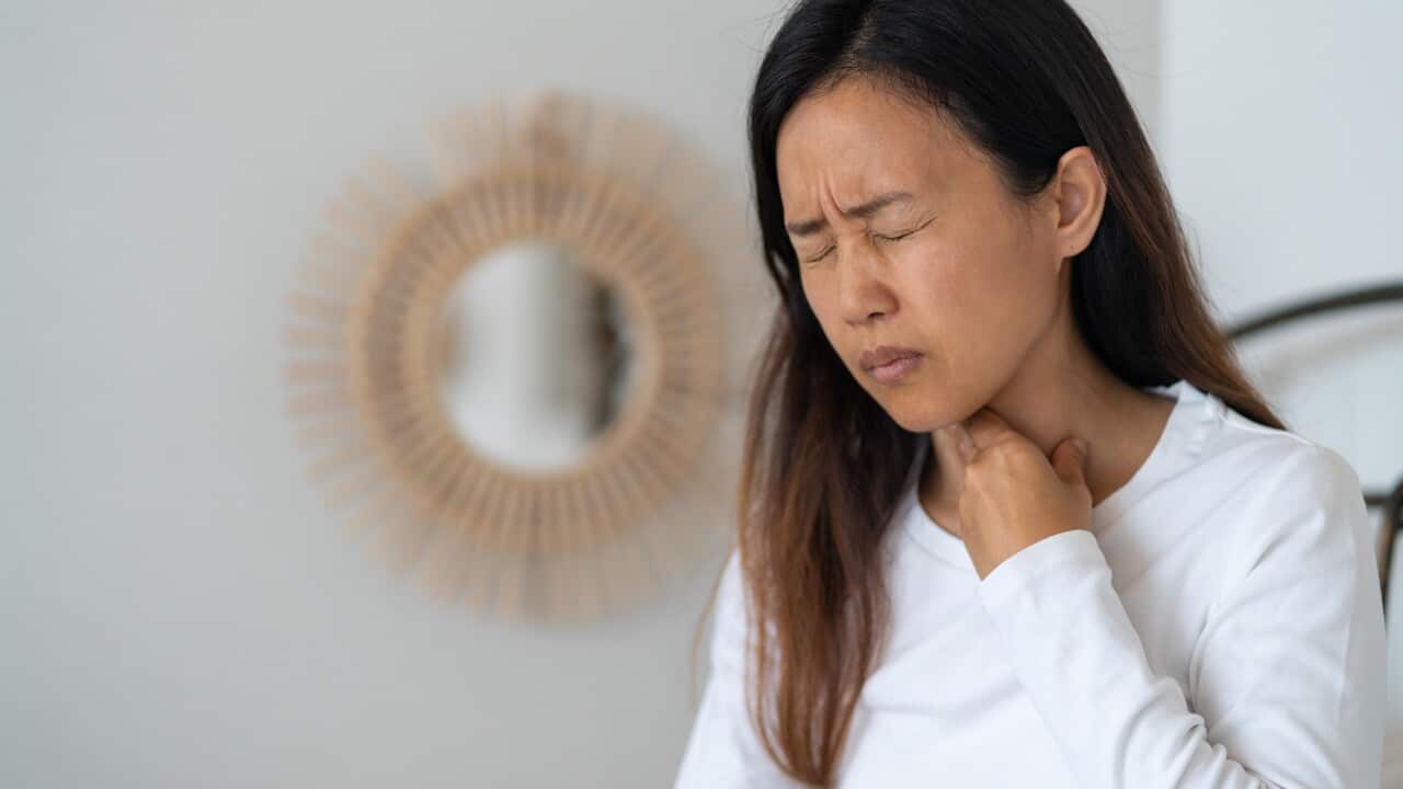A woman touching her throat in pain