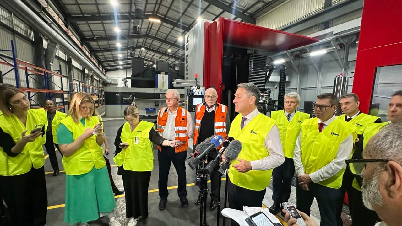A group of people in high vis standing around for a media press conference.