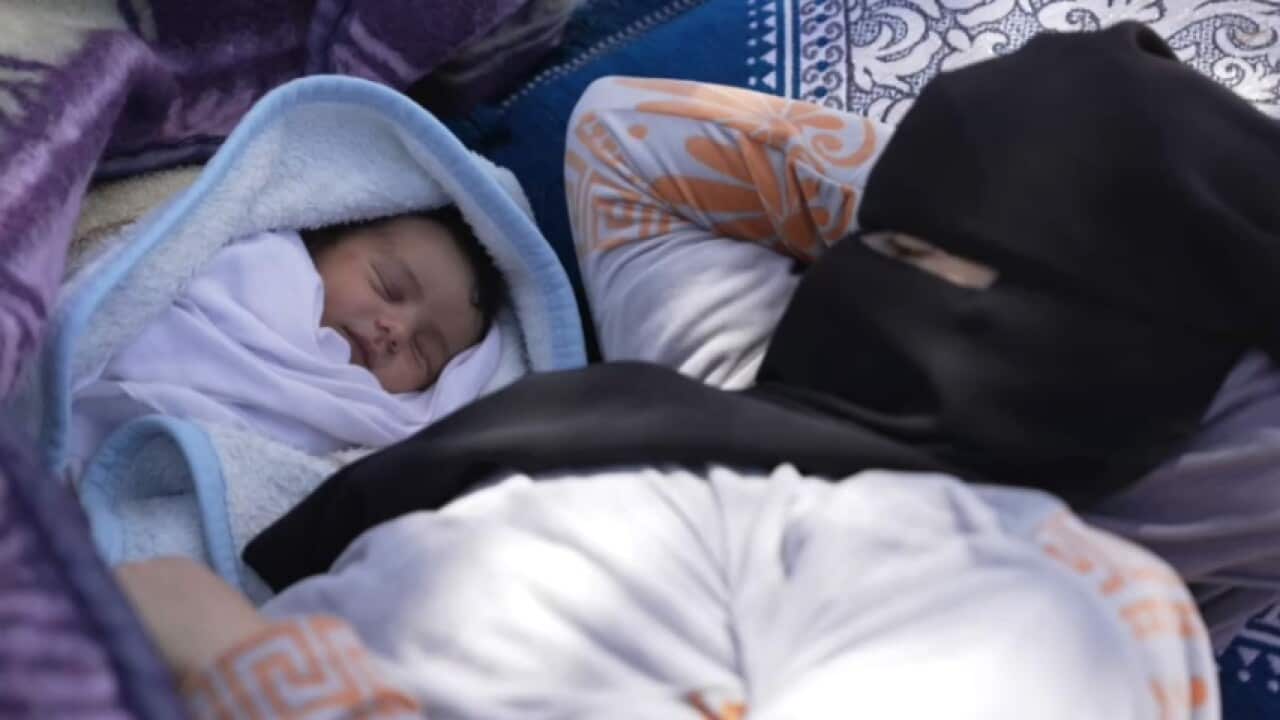 A woman and her newborn baby lying down.