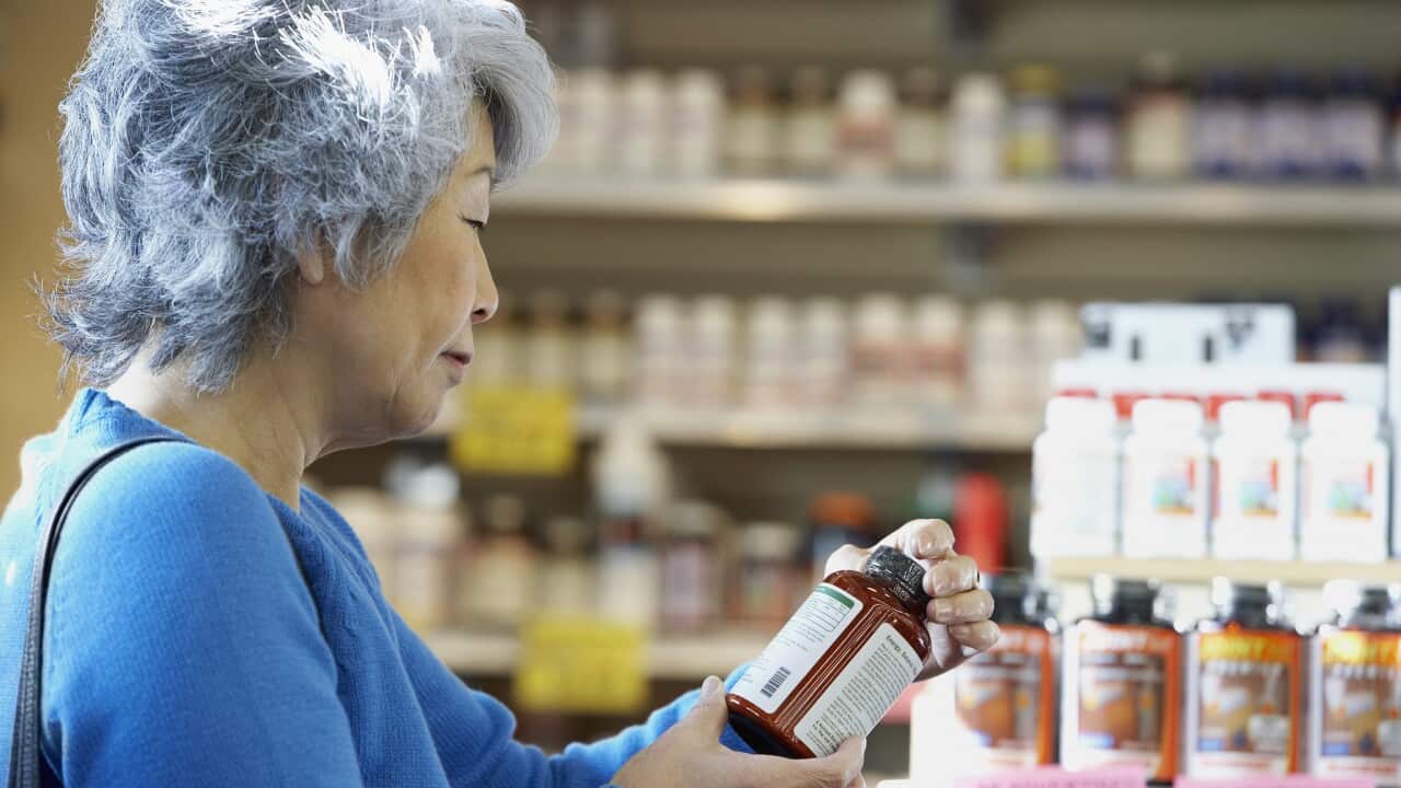 Senior Asian woman reading vitamin label