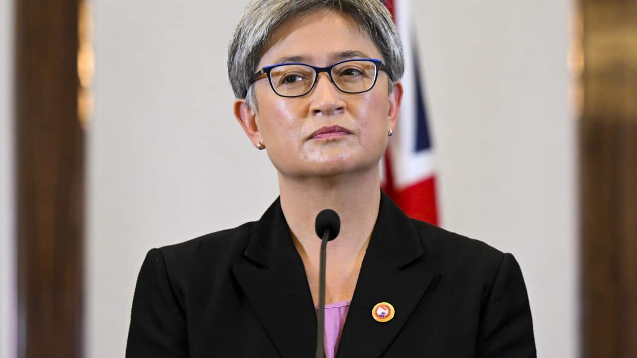 A woman standing at a lectern in front of a microphone.