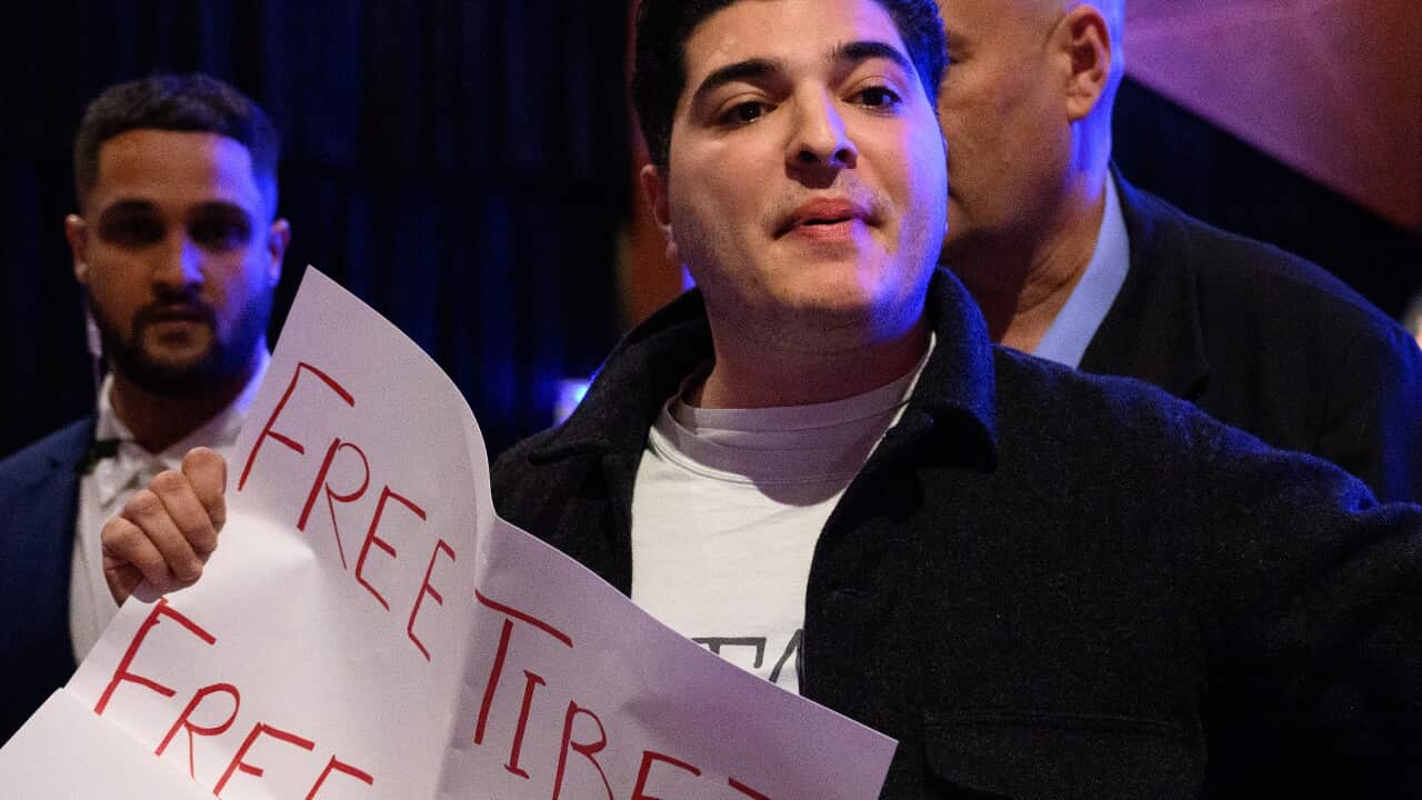 A man holds up a sign that says 'free Tibet, free East Turkestan, free Hong Kong'