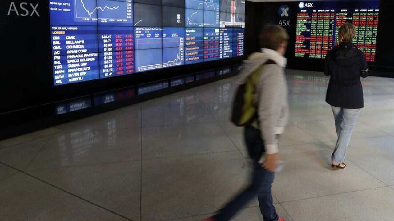Pedestrians look at display boards at the Australian Stock Exchange