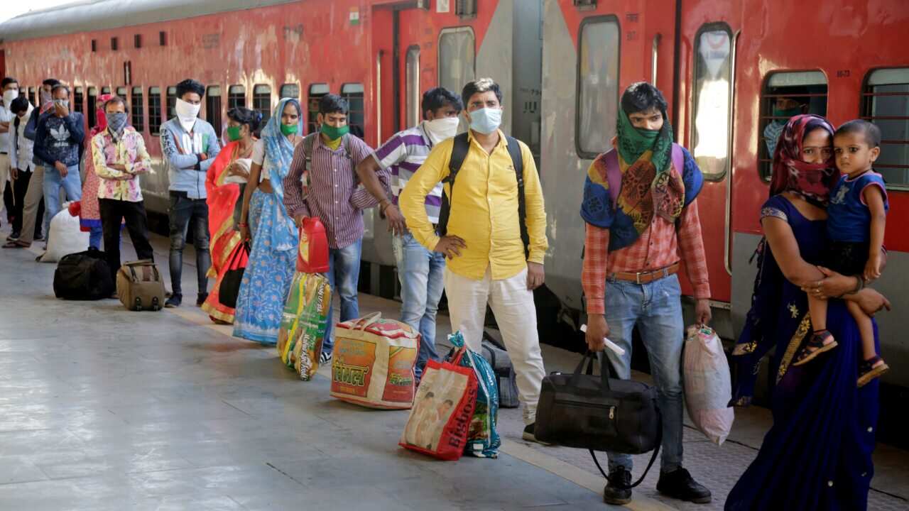 Indian migrated workers stands in queue to board a special train at a railway station in Ahmedabad, India.