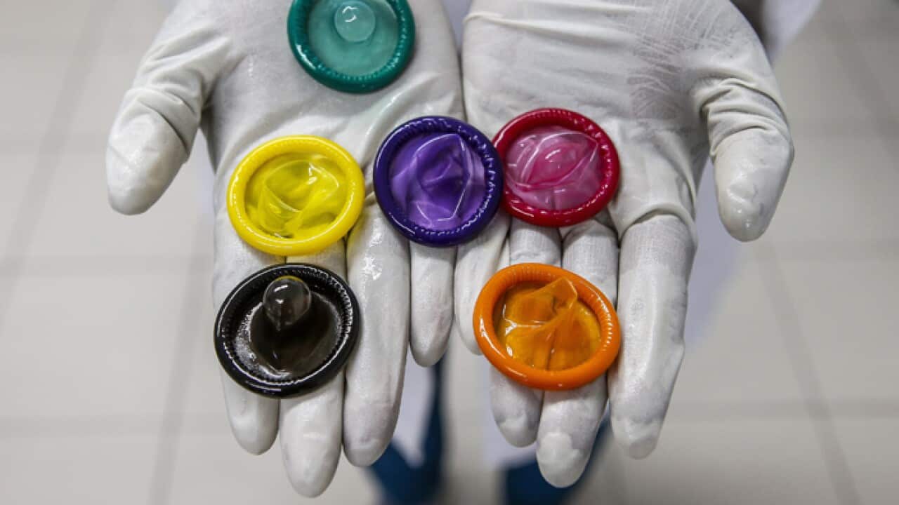 A worker holds a variety of colored condoms