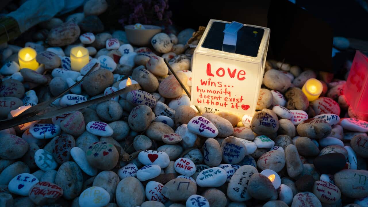 Pebbles with messages including "RIP" and "NO HATE", illuminated by a small light box that says "Love wins".