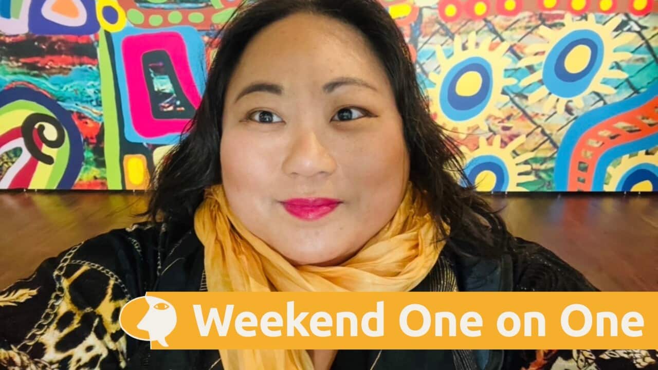 Dr Elaine Laforteza wearing a yellow scarf against a colourful mural.