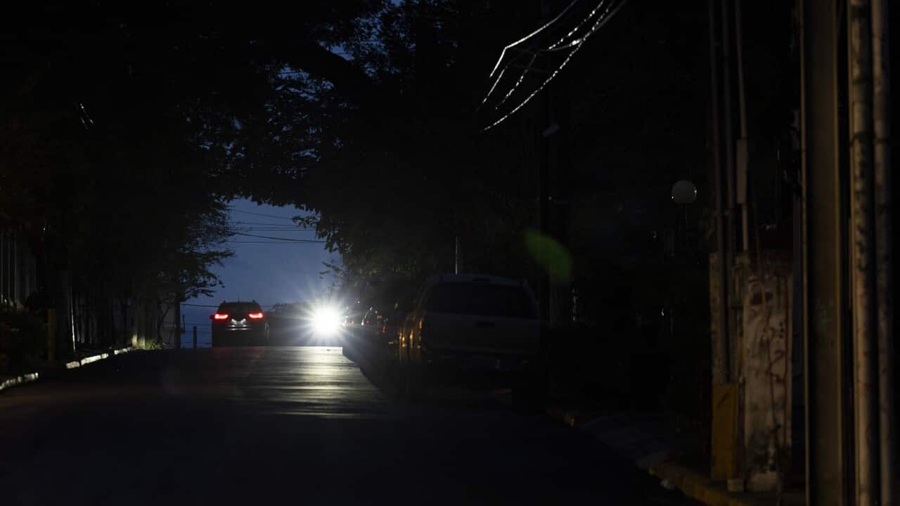 The headlights of a car light up a dark street.