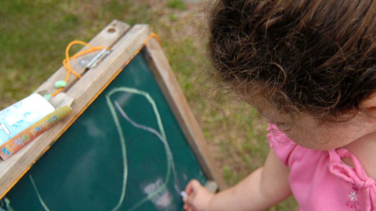 A stock image of a young girl drawing on a chalkboard